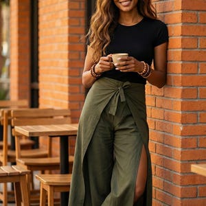 Rock an urban summer style in our Plain Army Green Palazzo Pants! 🏙️ These breathable boho fit wrap pants are your ultimate holiday companion for city explorations. The daring high side slit and chic tie-waist bring a stylish edge to a casual black t-shirt and sunglasses ensemble. ☕ Whether you're grabbing a coffee at a street cafe or walking around town, these lightweight wide-leg trousers ensure you stay cool, comfortable, and effortlessly fashionable all day long. A must-have travel piece!