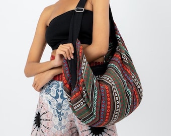 Può includere: Una grande borsa tote a righe colorate con una tracolla nera. La borsa è realizzata in tessuto intrecciato e presenta un motivo geometrico in tonalità di rosso, arancione, verde, blu e marrone.