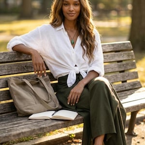 Enjoy casual everyday comfort with our Plain Army Green Palazzo Pants. 📖 Perfect for a relaxing holiday afternoon, these breathable boho fit wide-leg trousers feature a stylish side slit and a waist-defining front tie. Seen styled elegantly on a park bench with a classic tied white linen shirt and slip-on loafers. These versatile olive green wrap pants transition effortlessly from a morning coffee run to a tranquil afternoon reading session. Your new go-to sustainable summer wardrobe staple! ☕