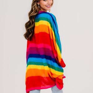 Pu&ograve; includere: Un top in stile kimono a righe arcobaleno vibrante. L'indumento colorato presenta bande orizzontali di rosso, arancione, giallo, verde, blu e viola. Il tessuto leggero drappeggia liberamente, creando una silhouette fluida. Il top &egrave; un capo audace.