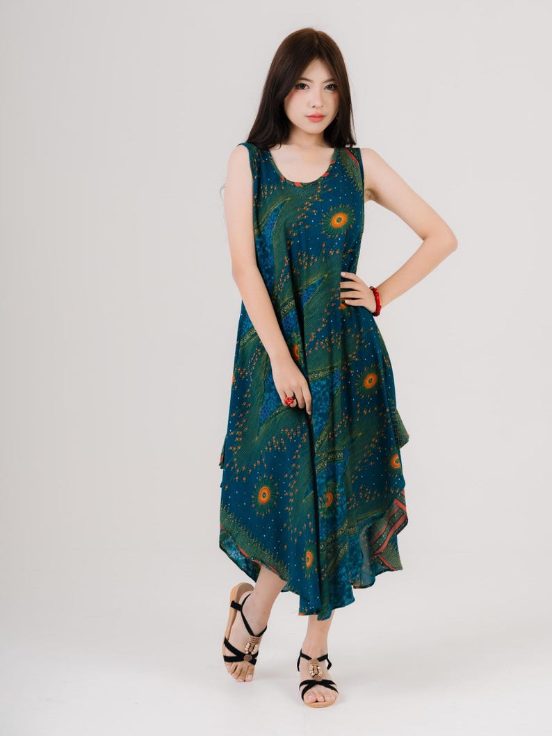 Maxi sleeveless dress with bold rainbow print, modeled by woman in black sandals. Great choice for beach days or casual outings.