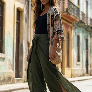 Travel in style with our Plain Army Green Palazzo Pants! ✈️ These highly breathable boho fit trousers are the perfect holiday staple for exploring colorful city streets. The comfortable wrap style with bold side slits and a tie-waist offers fantastic mobility. 🚶‍♀️ Flawlessly styled with white sneakers, a black tank, and a vibrant printed kimono for an ultimate tourist-chic look. Stay cool in the summer heat while looking totally effortlessly put-together in these flowy wide-leg pants. 🌍