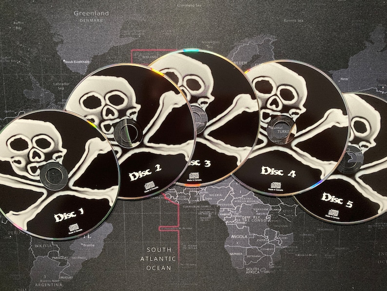 Może przedstawiać: Pięć srebrnych płyt CD z czarno-białymi wzorami czaszek i skrzyżowanych kości. Płyty CD są oznaczone jako "Dysk 1", "Dysk 2", "Dysk 3", "Dysk 4" i "Dysk 5".