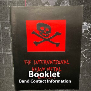 Może przedstawiać: Czarna książeczka z czerwonym logo czaszki i skrzyżowanych kości. Tekst "THE INTERNATIONAL HEAVY METAL BOOKLET Band Contact Information" jest wydrukowany na biało.