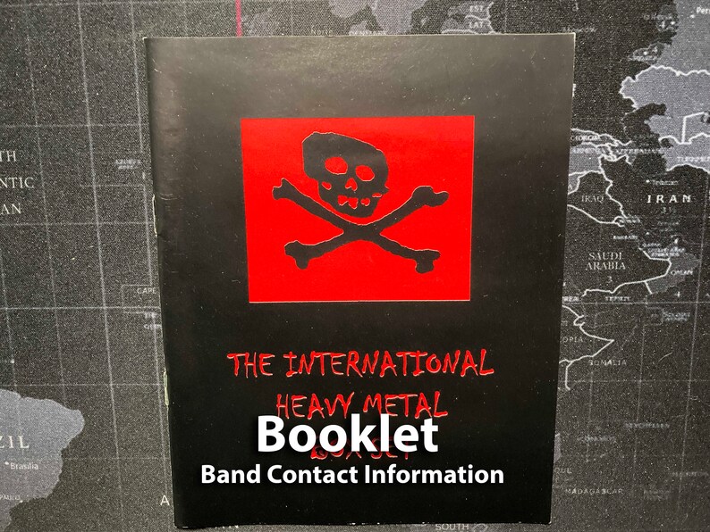 Może przedstawiać: Czarna książeczka z czerwonym logo czaszki i skrzyżowanych kości. Tekst "THE INTERNATIONAL HEAVY METAL BOOKLET Band Contact Information" jest wydrukowany na biało.