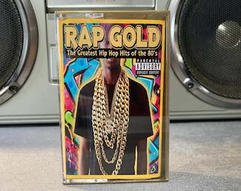 May include: A cassette tape with the album cover for "Rap Gold: The Greatest Hip Hop Hits of the 80's." The cover features a person wearing gold chains, with graffiti art in the background. The tape has a parental advisory warning.