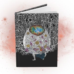 Black hardcover notebook (front, open with pages visible) with collage artwork featuring a figure with a baby, goddess imagery, a drawing of a neuron, floral imagery and a photo of a galaxy