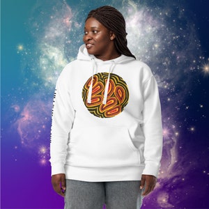 Puede incluir: Sudadera con capucha blanca con un diseño circular negro y amarillo con formas abstractas. El diseño está centrado en la parte delantera de la sudadera. La sudadera tiene una capucha con cordón y un bolsillo canguro.