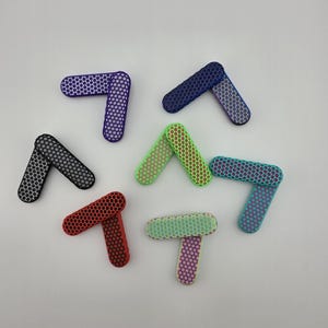 May include: A collection of seven colorful, angled, geometric shapes. Each shape is a different color, including black, red, green, blue, and purple. The shapes have a honeycomb pattern and are arranged on a white background.