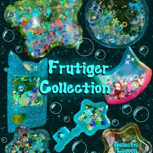 Pode incluir: Uma cole&ccedil;&atilde;o de pingentes shaker de resina em v&aacute;rias formas, incluindo estrelas, um console de jogo port&aacute;til e uma chave, preenchidos com glitter, mi&ccedil;angas e lantejoulas coloridas. O texto diz Frutiger Collection e Galactic Lagoon com links.