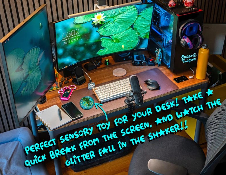 Pode incluir: Um brinquedo sensorial redondo, verde e cheio de glitter sobre uma mesa de madeira. A mesa inclui um computador com dois monitores, teclado, rato, microfone, smartphone, caderno e uma garrafa de &aacute;gua amarela. O texto diz: PERFECT SENSORY TOY FOR YOUR DESK! TAKE A QUICK BREAK FROM THE SCREEN, AND WATCH THE GLITTER FALL IN THE SHAKER!