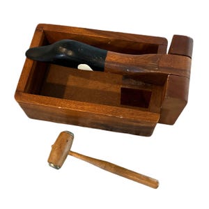 May include: Wooden nutcracker with a duck head design and a separate wooden mallet. The nutcracker is brown with black and white painted details.