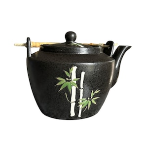 Peut inclure: Théière en céramique noire avec un motif de bambou. La théière a une poignée en bois et un bec.