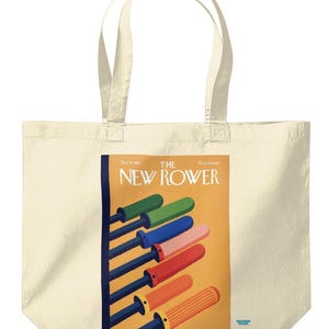 Puede incluir: Bolso tote color crema con una portada de revista vintage. La portada muestra remos coloridos en verde, azul, rosa, rojo y naranja sobre un fondo amarillo. El texto "THE NEW ROWER" es visible.