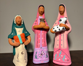 May include: Three hand-painted ceramic figurines depicting the three wise men. The figures are dressed in colorful robes with intricate designs. The figure on the left holds a butterfly, the middle figure holds a small pot, and the figure on the right holds a small lamb.
