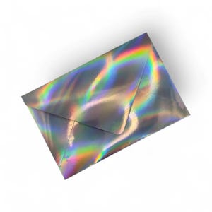 May include: A holographic envelope with a silver base and a rainbow sheen. The envelope is rectangular and has a flap closure. The iridescent surface reflects light, displaying a spectrum of colors.