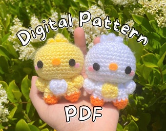 May include: A digital pattern for crocheting two small chick plushies. One chick is yellow with a white heart, and the other is white with a yellow heart. Both chicks have orange feet. The pattern is available as a PDF download.