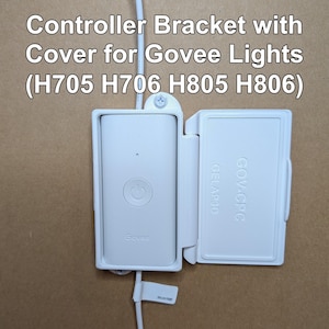 May include: A white controller bracket with a cover for Govee lights. The bracket is open, revealing the controller with a power button. The text "Controller Bracket with Cover for Govee Lights (H705 H706 H805 H806)" is displayed at the top.