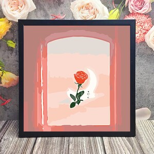 May include: A framed print of a red rose with a crescent moon behind it. The rose is in a pink and white archway.