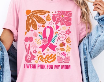 Peut inclure: T-shirt rose avec un motif floral et un ruban rose. Le texte "I wear pink for my mom" est imprimé sur le t-shirt.