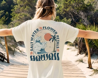 May include: White t-shirt with a graphic print of a sunset, palm trees, and waves. The text "Salt Water Flower Petals Hawaii" is printed around the graphic.
