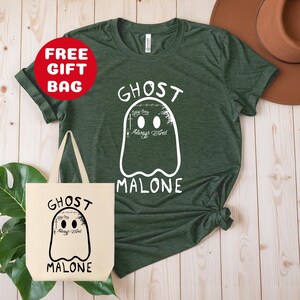 Puede incluir: Una camiseta verde con un gr&aacute;fico de fantasma blanco y el texto "Ghost Malone" con las palabras "Always Tired" dentro del fantasma. Tambi&eacute;n se muestra una bolsa de mano blanca con el mismo gr&aacute;fico y texto.