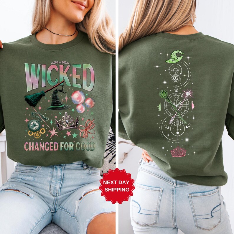 Puede incluir: Sudadera verde oliva con las palabras "WICKED" y "CHANGED FOR GOOD". La parte delantera presenta un sombrero de bruja, una escoba y burbujas. La parte trasera tiene un dise&ntilde;o vertical con un sombrero de bruja y otros s&iacute;mbolos.