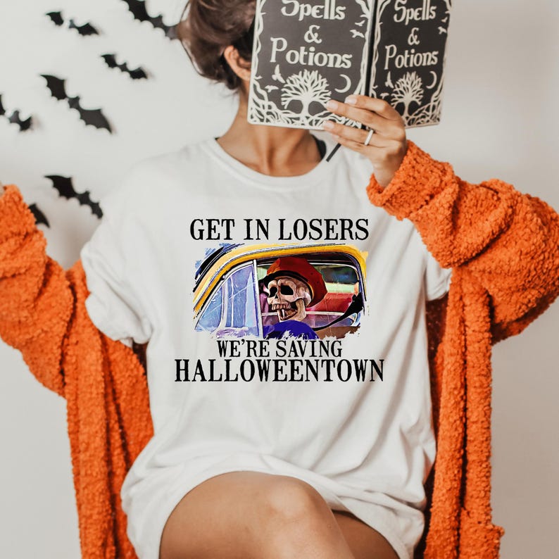 May include: White t-shirt with a graphic of a skeleton driving a car with the text "Get in losers, we're saving Halloweentown".
