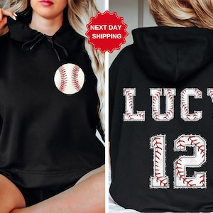 May include: Black hooded sweatshirt with a baseball graphic on the front and the name "LUCY" and the number "12" on the back, both with a baseball stitch design.