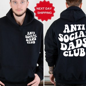 May include: Black hooded sweatshirt with white text that reads "Anti Social Dads Club" in a retro font. The text is on the back of the sweatshirt. The front of the sweatshirt has the same text in a smaller size on the left chest.