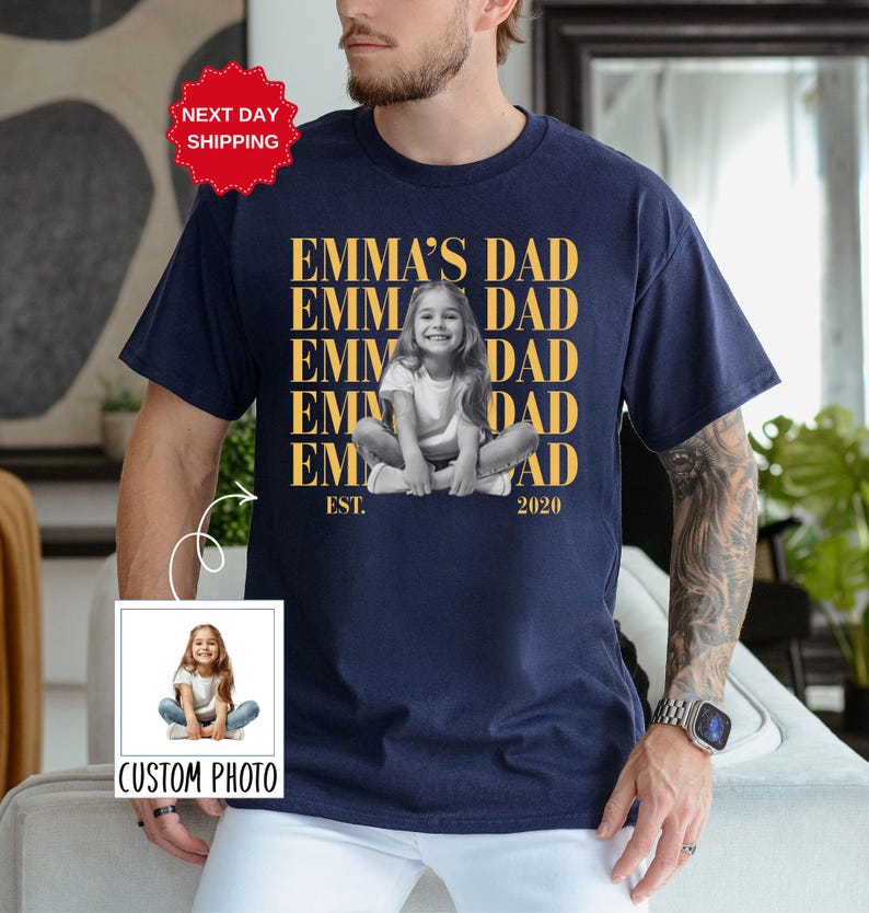 Puede incluir: Camiseta azul marino con una foto personalizada de un ni&ntilde;o y el texto "EMMA'S DAD" repetido verticalmente. La camiseta tambi&eacute;n incluye el texto "EST. 2020" y una pegatina de "NEXT DAY SHIPPING".
