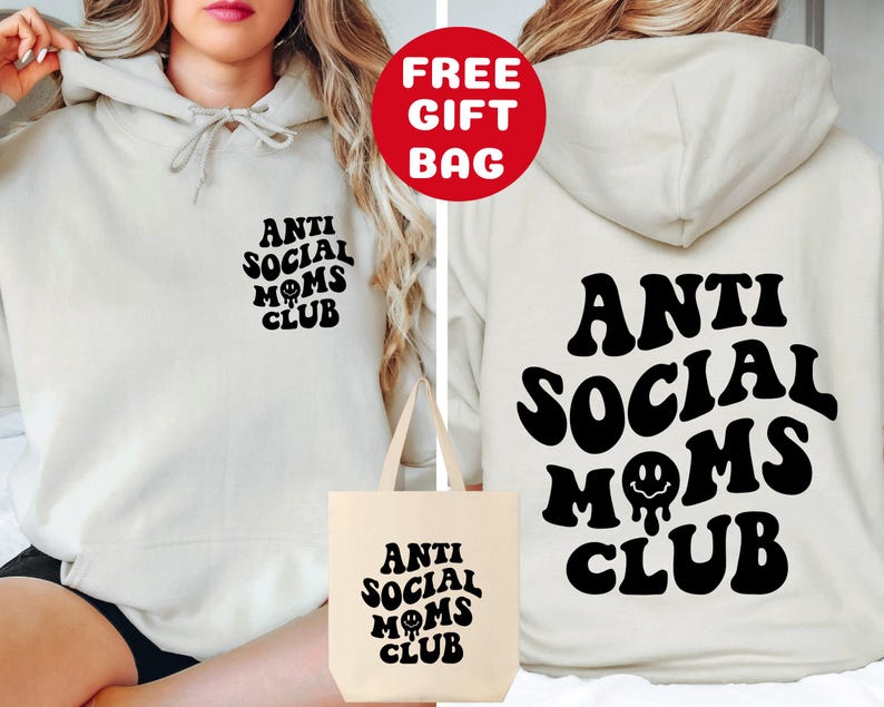 May include: A white hoodie with the text "Anti Social Moms Club" in black, retro-style lettering. The hoodie is shown being worn by a person and comes with a matching tote bag.
