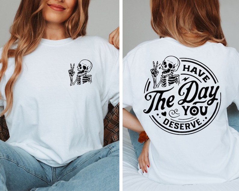 May include: White t-shirt with a black skeleton graphic on the front and a black circle graphic on the back that says "Have the Day You Deserve".