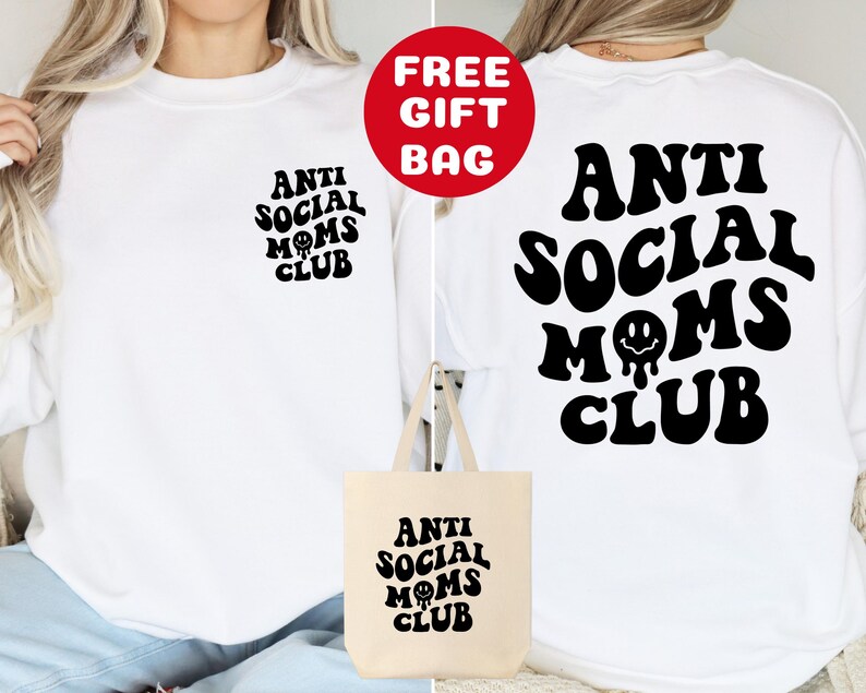 May include: White long-sleeve sweatshirt with black text that reads "Anti Social Moms Club" with a smiley face. A white tote bag with the same text and design is included.