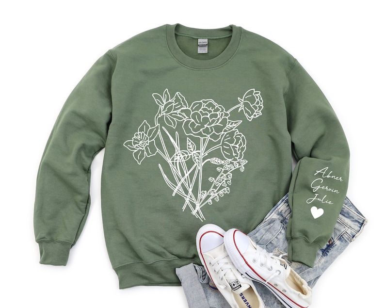 May include: A green sweatshirt with a white floral design and the names "Abner, Gerwin, Julie" on the sleeve.