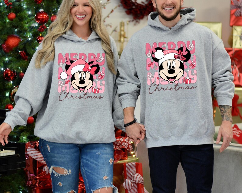 May include: A matching set of gray hoodies with a pink and white "Merry Christmas" design featuring Mickey Mouse. The hoodies have a kangaroo pocket and a drawstring hood.