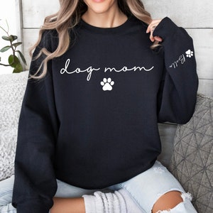 May include: Black sweatshirt with the text "dog mom" in white cursive lettering and a white paw print below. The left sleeve has a white paw print and the text "Ball" in white cursive lettering.