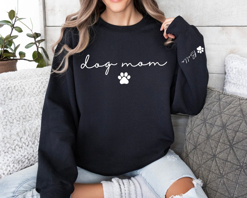 May include: Black sweatshirt with the text "dog mom" in white cursive lettering and a white paw print below. The left sleeve has a white paw print and the text "Ball" in white cursive lettering.
