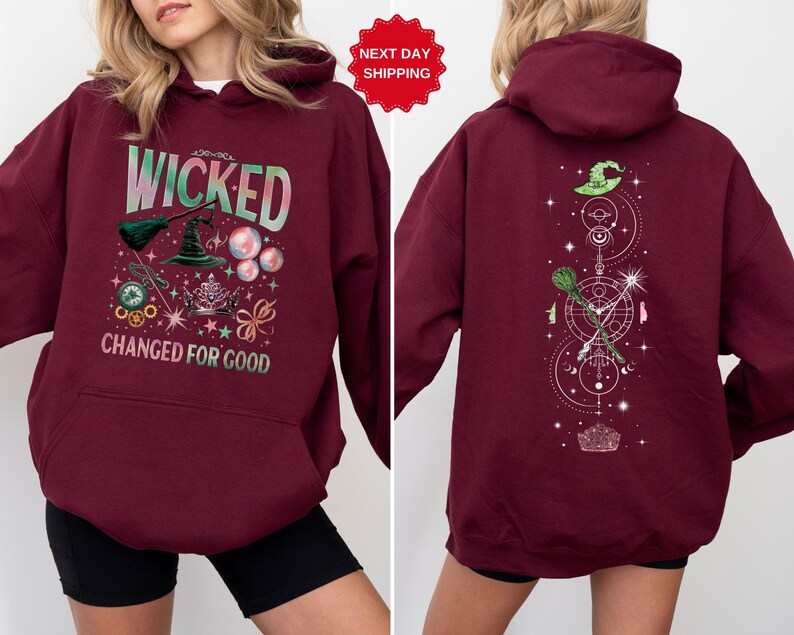 Puede incluir: Sudadera con capucha burdeos con el texto "WICKED CHANGED FOR GOOD" y un gr&aacute;fico de un sombrero de bruja, una escoba y otros elementos m&aacute;gicos. La parte trasera de la sudadera presenta un dise&ntilde;o similar con un sombrero de bruja y una escoba.