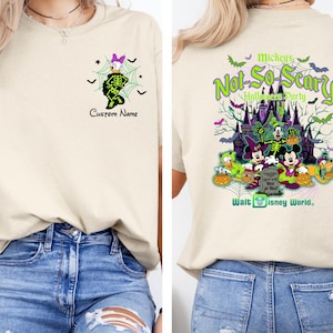 K&ouml;nnte beinhalten: Cremefarbenes T-Shirt mit Halloween-Motiv. Auf der Vorderseite ist Daisy Duck im Skelettkost&uuml;m mit dem Text "Custom Name" abgebildet. Auf der R&uuml;ckseite ist eine gruselige Schlossszene mit Disney-Figuren und dem Text "Mickey's Not-So-Scary Halloween Party" zu sehen.