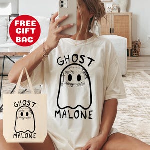 May include: A white tote bag and a white t-shirt with a black ghost graphic and the text "Ghost Malone" printed on them. The ghost has the words "Easy Baby" and "Always Tired" written on it.