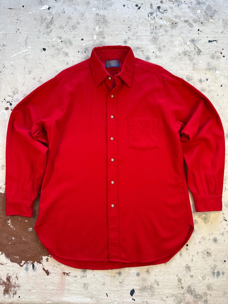 Puede incluir: Una camisa de manga larga de color rojo s&oacute;lido con cuello en punta, un bolsillo en el pecho en el lado izquierdo y una tapeta frontal con botones de color claro. La camisa incluye una etiqueta de la marca Pendleton en el interior del cuello.