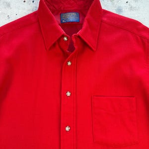 Puede incluir: Una camisa de manga larga de color rojo brillante con cuello cl&aacute;sico, tapeta frontal con botones met&aacute;licos y un bolsillo en el pecho. El interior del cuello incluye una etiqueta azul de la marca Pendleton y un forro rojo acolchado.