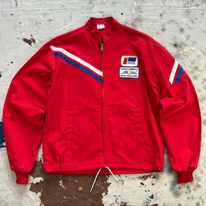 May include: A red zip-up jacket with white and blue stripes on the sleeves and a small patch on the chest. The patch reads "Piper Aircraft Owners & Pilots Association". The jacket has a drawstring at the waist and red cuffs.