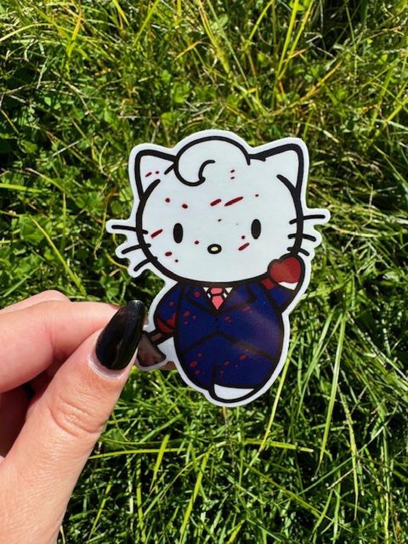 Puede incluir: Un gato de dibujos animados blanco con manchas rojas, vistiendo un traje azul y una corbata roja, sosteniendo un coraz&oacute;n rojo. El gato tiene un fondo blanco.
