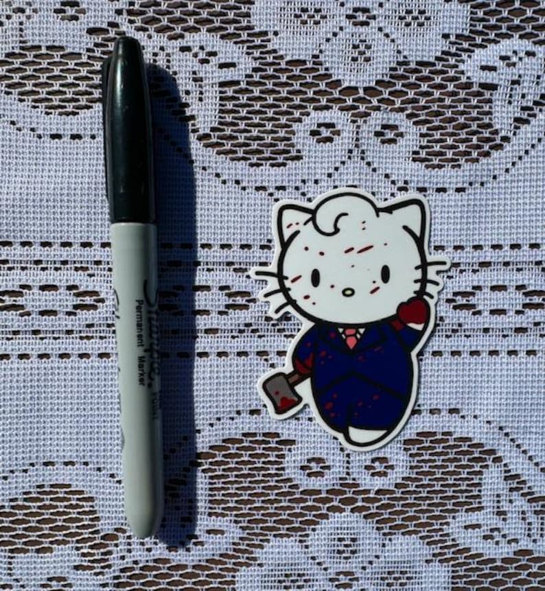 Puede incluir: Un personaje blanco de Hello Kitty con salpicaduras de sangre roja en la cara, vistiendo un traje azul y sosteniendo un hacha ensangrentada. El personaje est&aacute; en un estilo de dibujos animados.