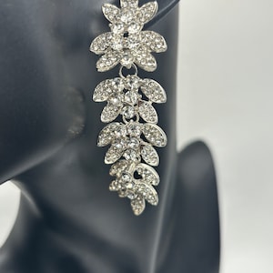 May include: Silver dangle earrings with a cascade of clear crystal flower designs.