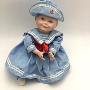 Bambola vintage in porcellana con vestito da marinaio blu e bianco, tema nautico e fiocco rosso, 25 cm.
