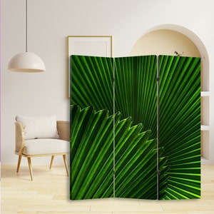 Puede incluir: Un separador de ambientes de tres paneles con un dise&ntilde;o de hoja de palmera verde. Los paneles son de madera y tienen un acabado natural.