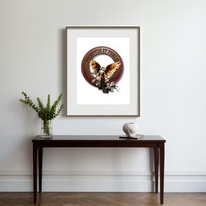 May include: A framed print of a red circle with a gold winged figure inside. The text "PROMPTUS ET FIDELIS" is written around the circle.